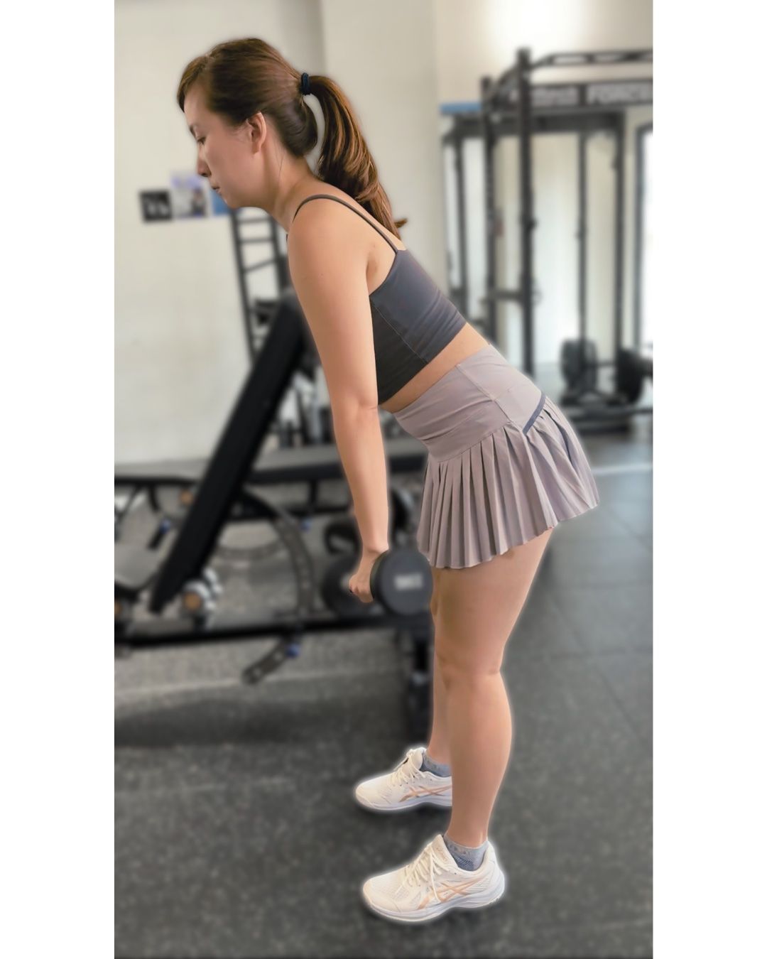 A client, side on, hinging with a dumbbell in each hand.