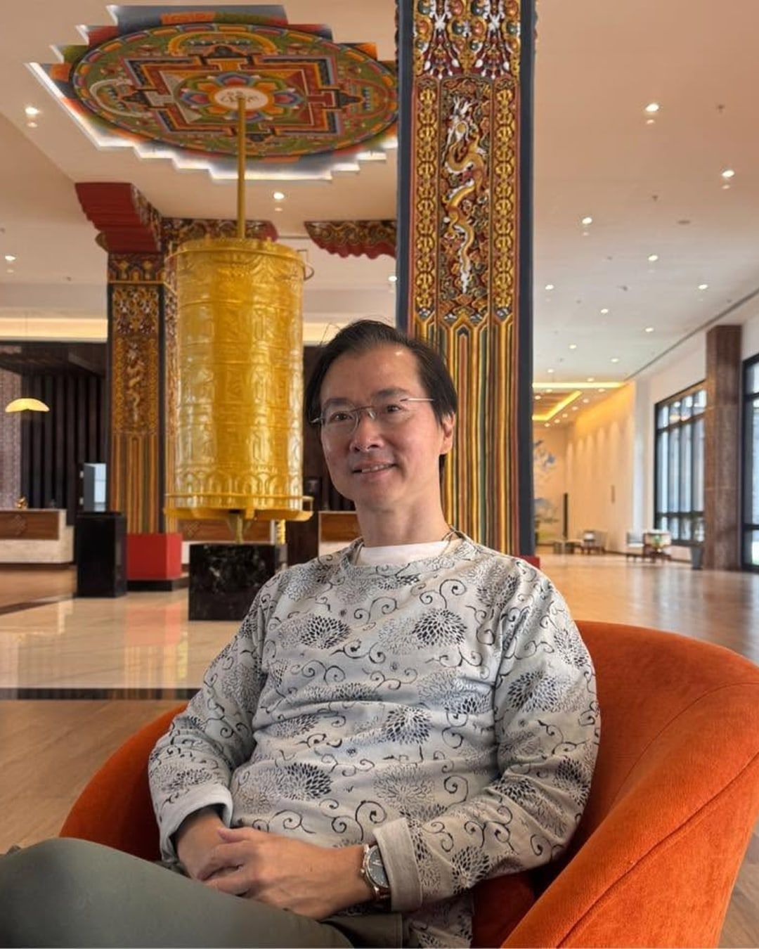 A client seated in an armchair in a hotel lobby, smiling.