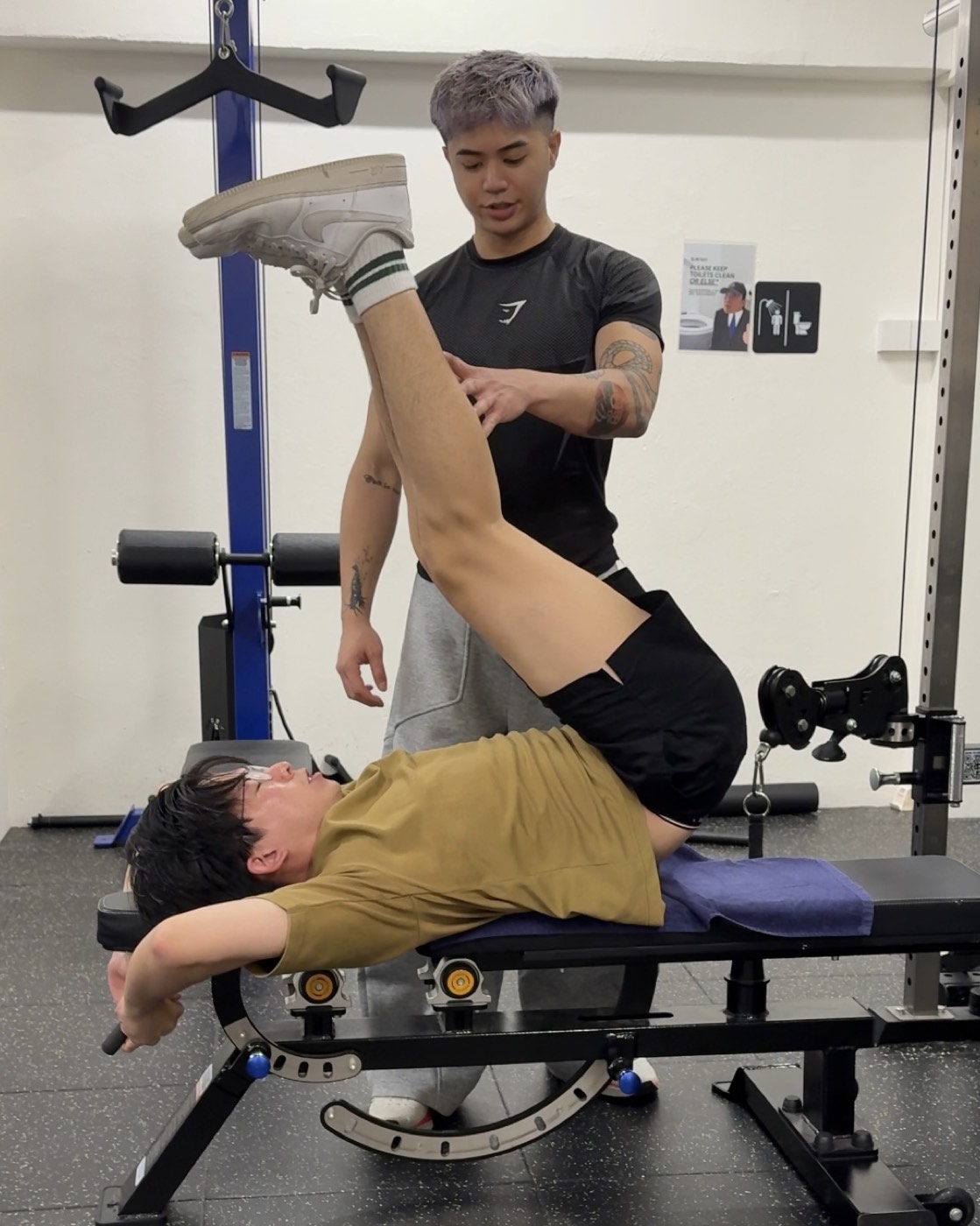Fred assisting a client through a controlled supine leg raise on a bench.