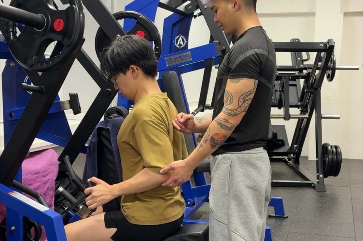 Fred coaching a client mid-set, hand on the machine.
